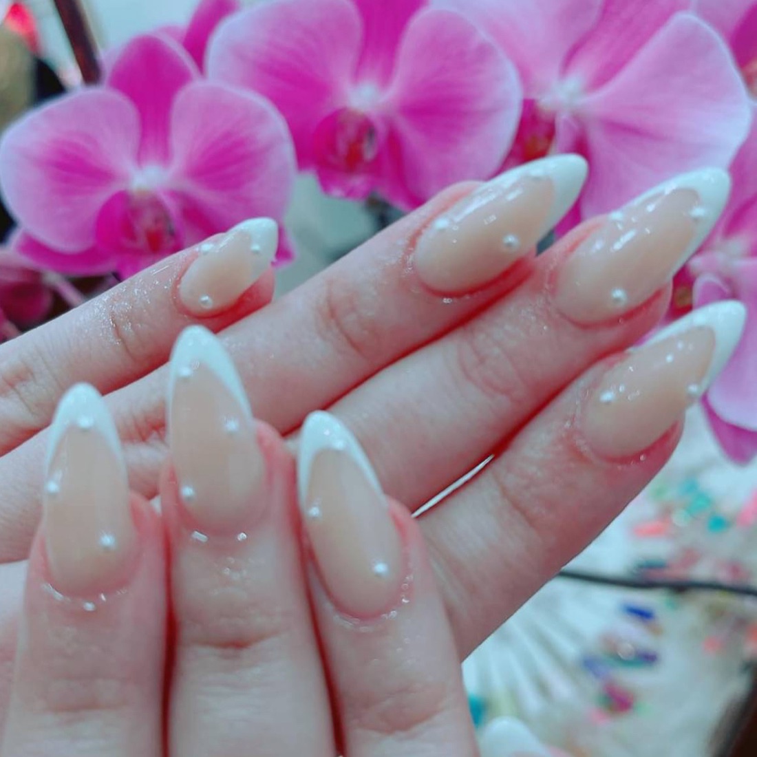 Almond-shaped nails with a soft white French tip and pearl detail, finished at Moon Beauty in Shoreditch