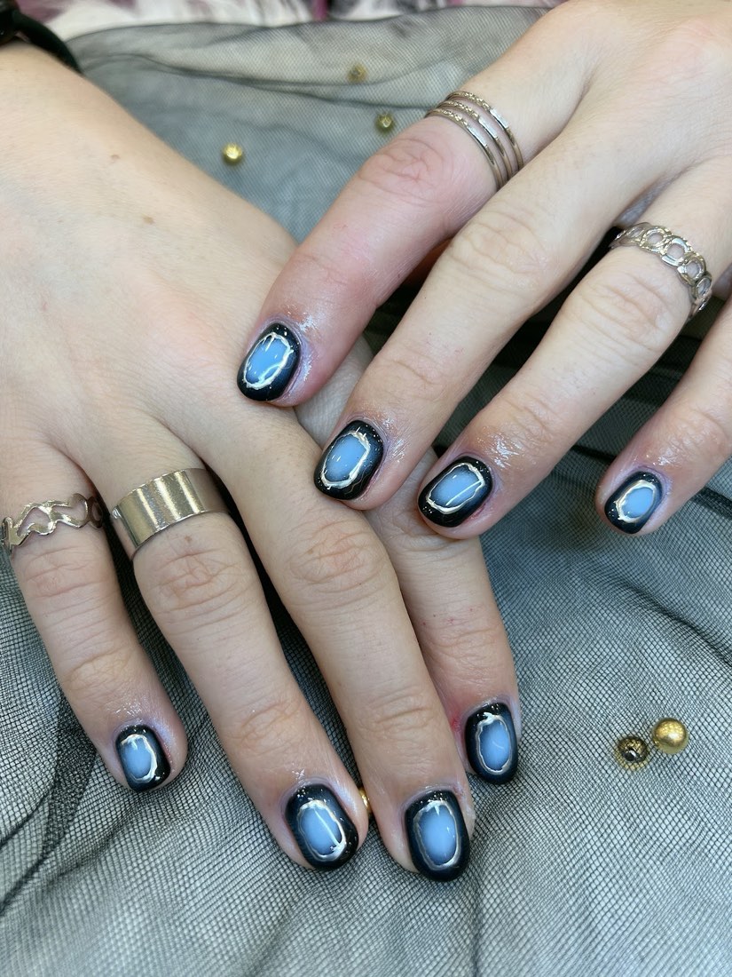 Short square nails in a black and periwinkle stained-glass design outlined in gold